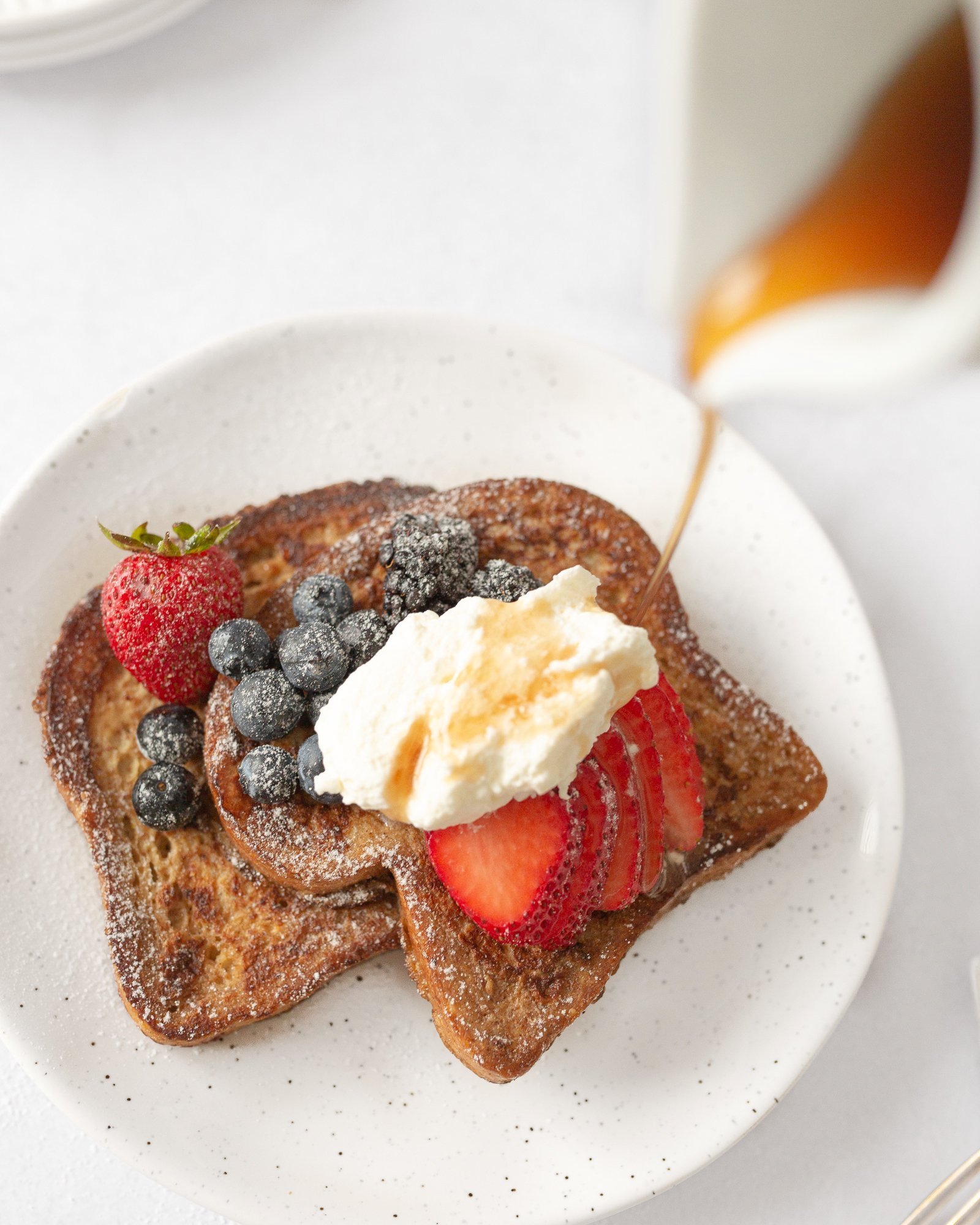 Classic French Toast with Berries plated and drizzled with maple syrup.