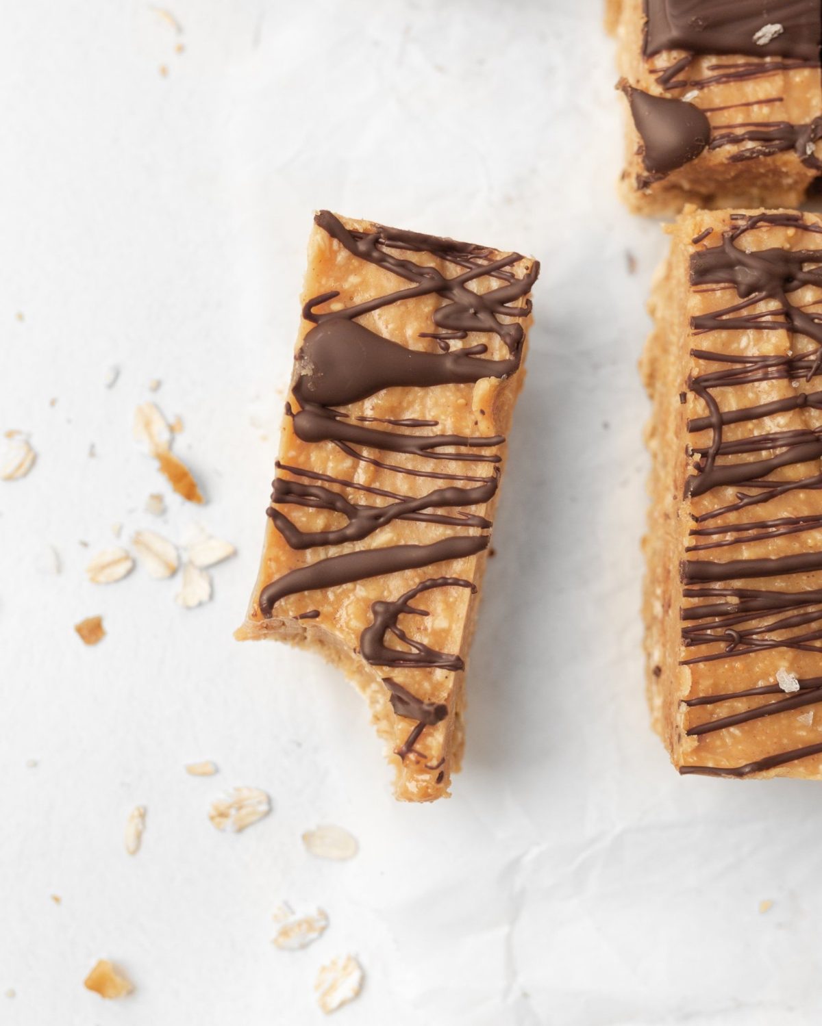 A single peanut Butter protein bar with a bite taken out of it on parchment paper.