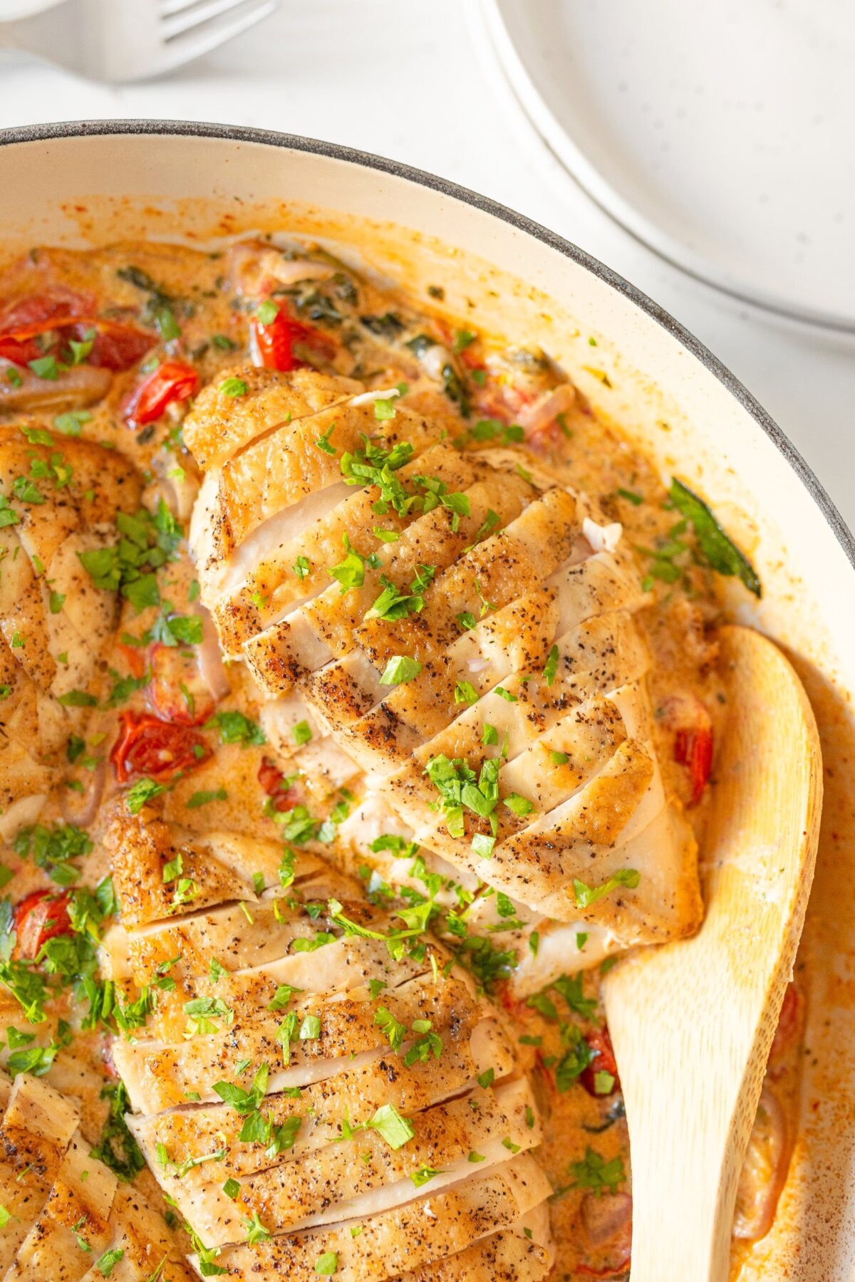 Baked Boursin Chicken with Spinach and Tomatoes cooked in a pan and garnished with fresh parsley.