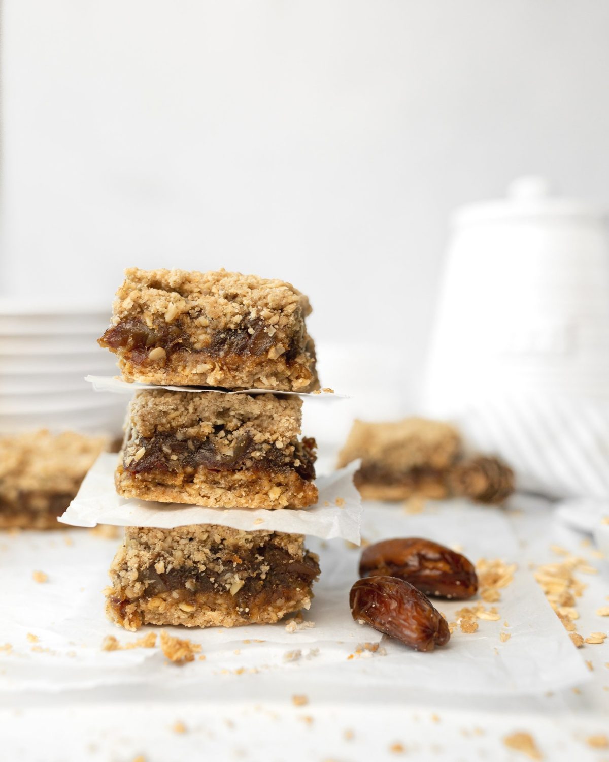 Gluten-free Chewy Date Bars stacked on parchment (straight on)