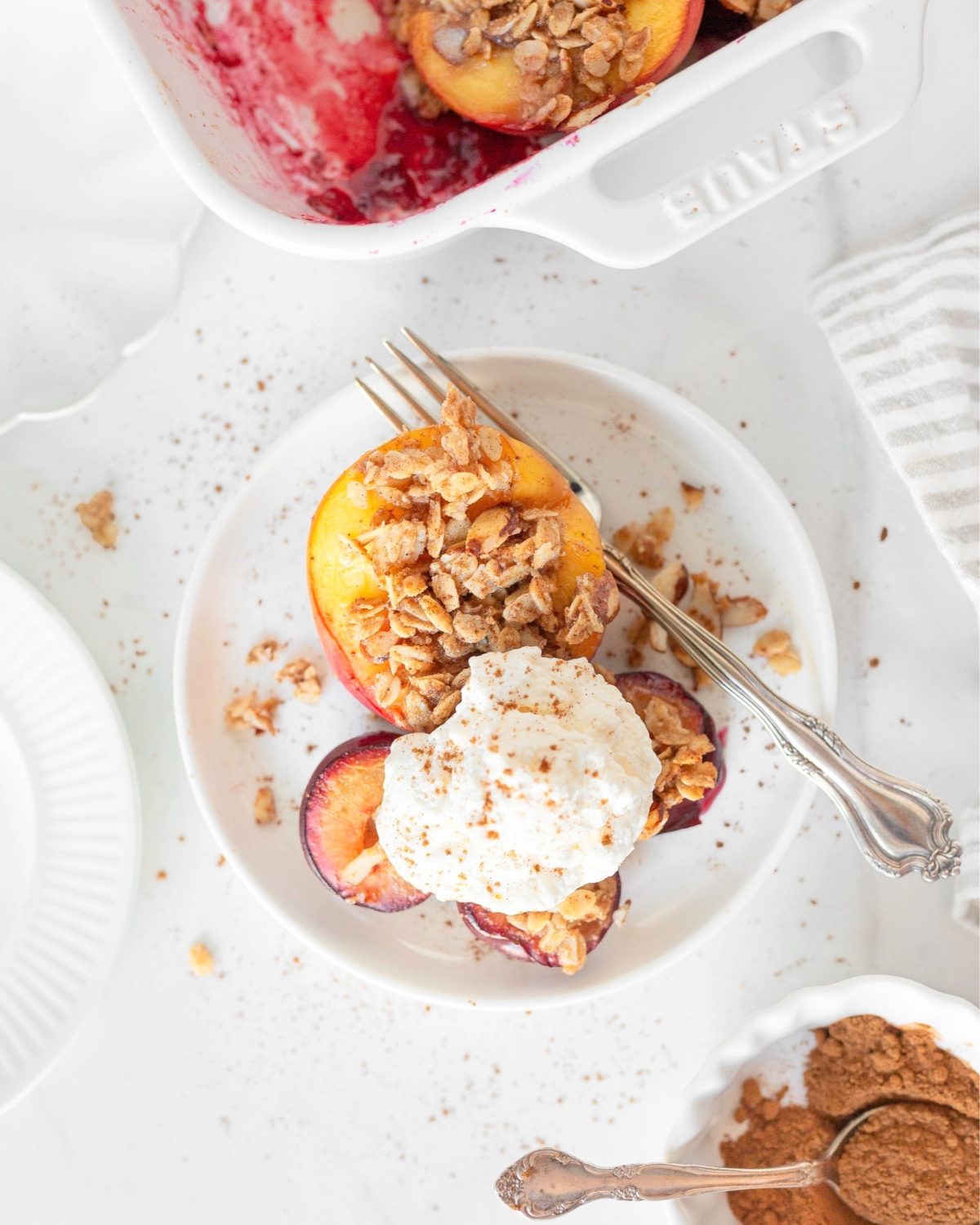 Baked Stone Fruits with Oats and Almonds plated and topped with whipped cream.