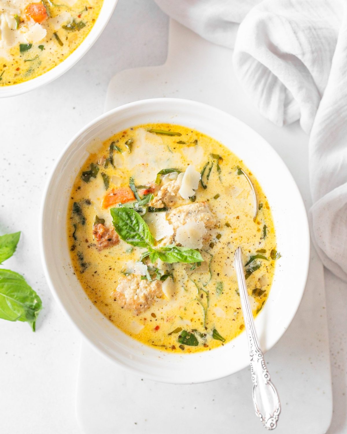 Creamy Tuscan Chicken Meatball Soup in a bowl with a spoon.