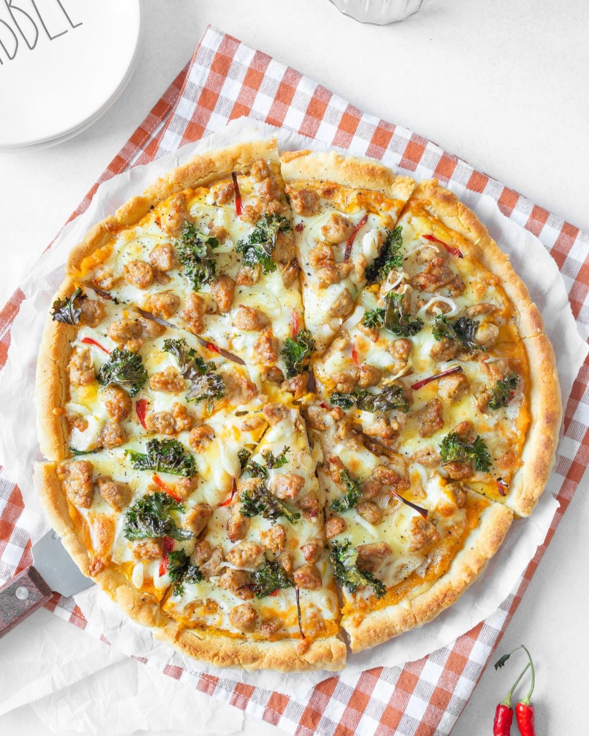 Pizza with Pumpkin, Chorizo and Kale cut on parchment paper.