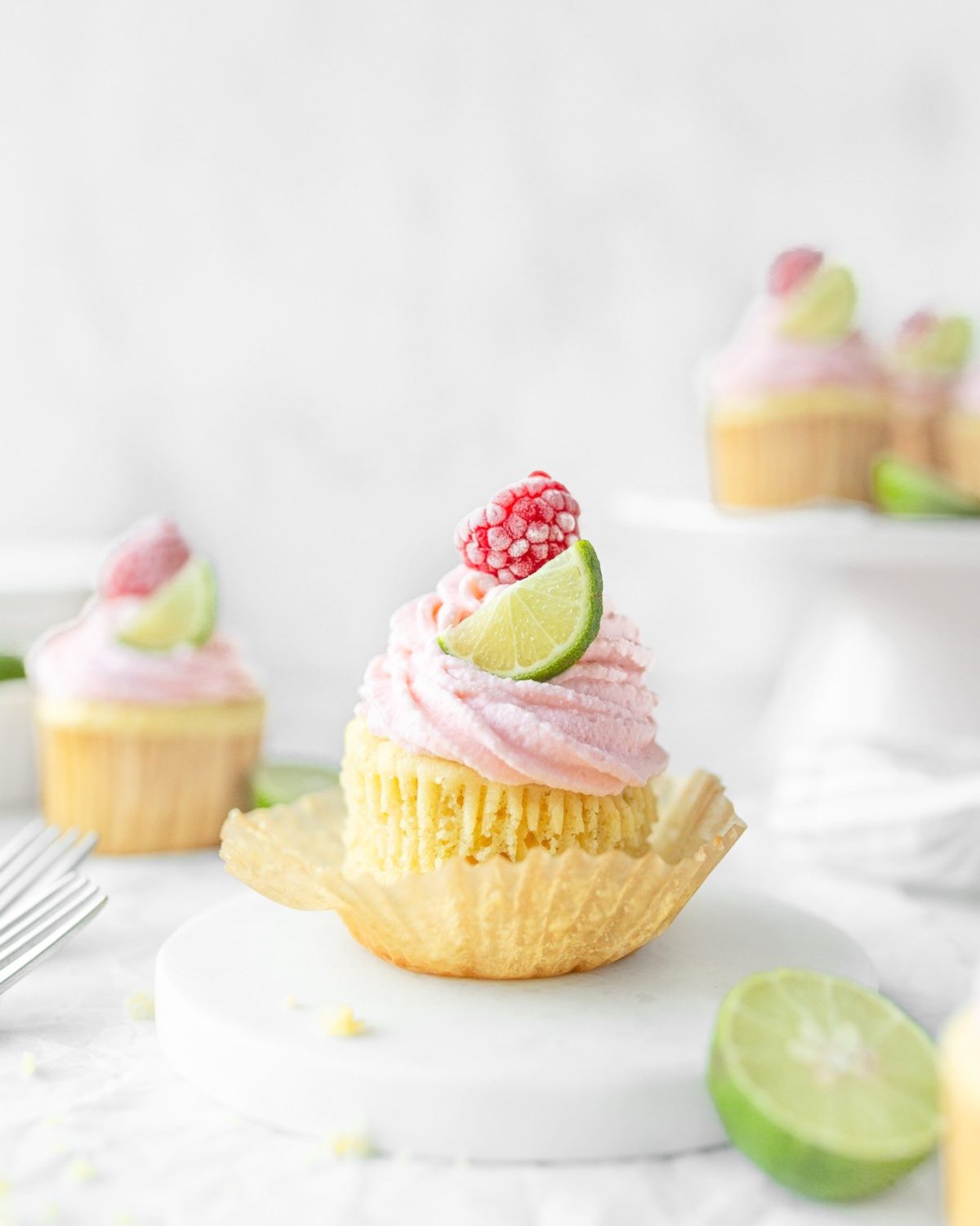 Gluten Free Key Lime Cupcakes garnished with lime slices and raspberries.