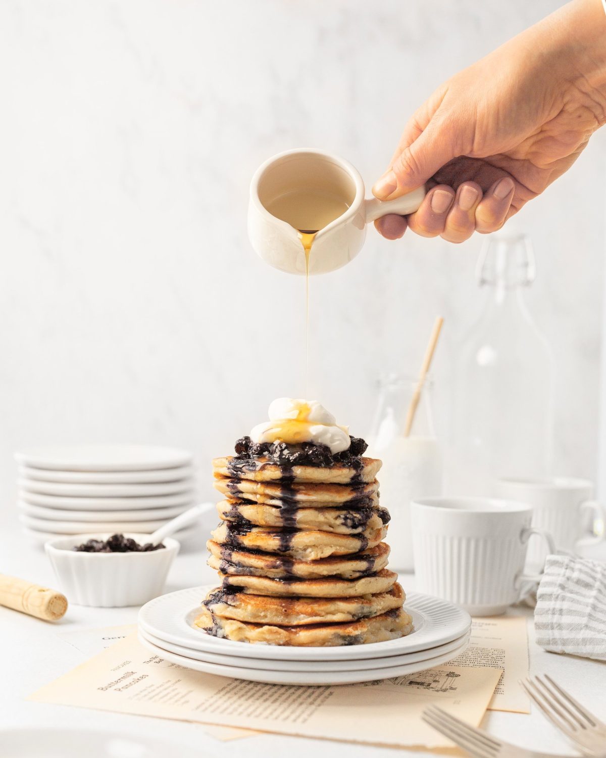 A stack of Gluten Free Blueberry Pancakes on a plate with syrup drizzled on top.