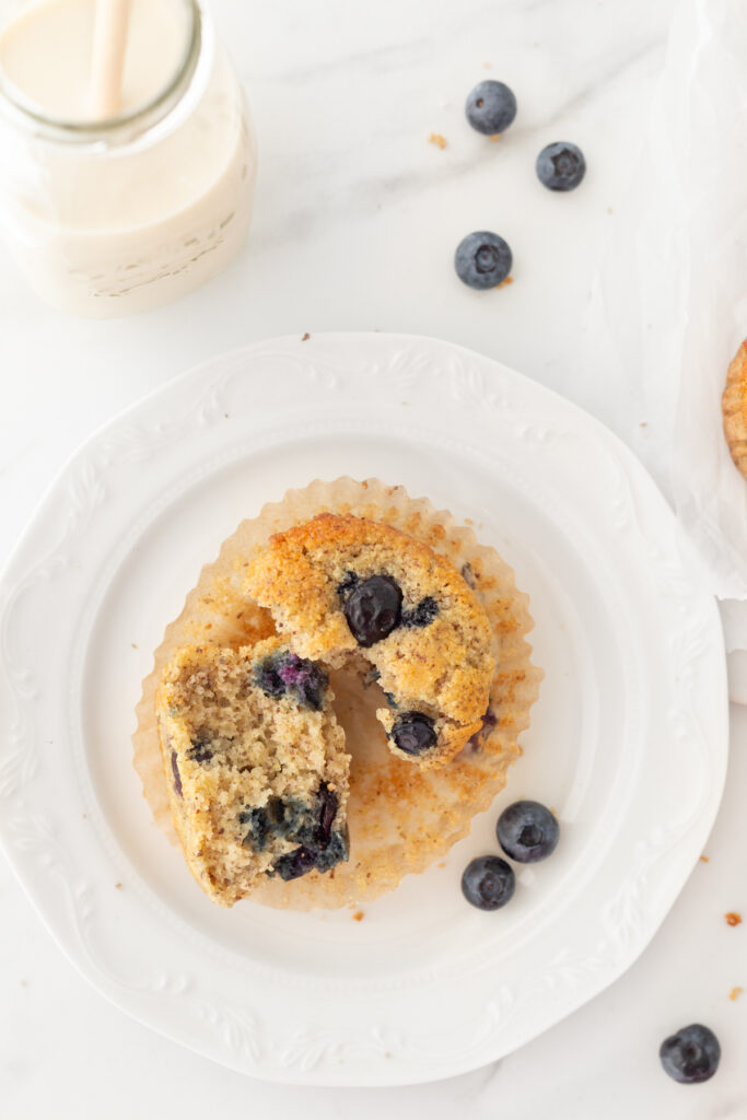 An Almond Flour Blueberry Muffin pulled apart in half on a small plate.