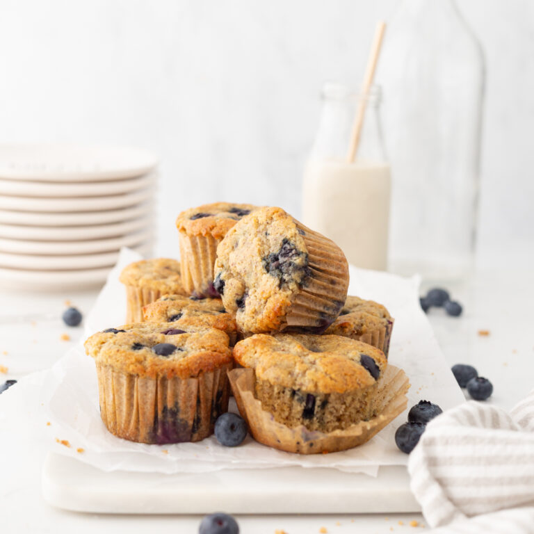 Almond Flour Blueberry Muffins on parchment paper on a marble serving board.